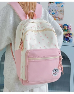 Detail of pink and white star pattern backpack with branded rubber logo on front pocket