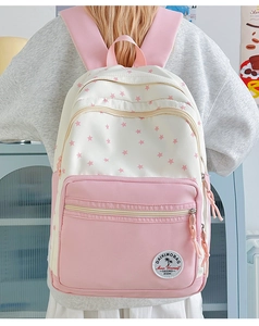 Detail view of pink and beige star pattern backpack with branded label and wide straps