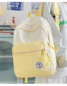 Detail of yellow star-patterned canvas backpack with multi-layer storage on model