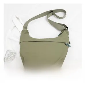 Olive green nylon crescent bag detail showing size comparison with a smartphone