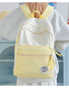 Close-up of yellow and white student backpack with star patterns and logo embroidery