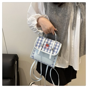Detail of light blue plaid backpack featuring apple logo and crossbody strap on model