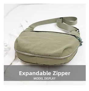 Detail view of khaki crescent bag with expandable bottom zipper for increased capacity