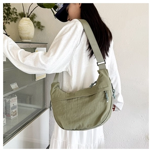 Close-up of bean green nylon crescent bag with adjustable wide strap and pleated texture