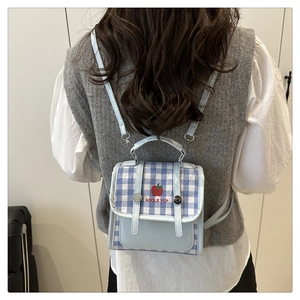 Detail of mini checkered backpack with apple embroidery and blue fabric textures
