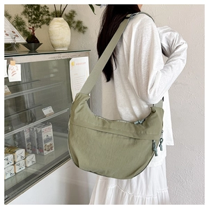 Detail of olive green crescent shoulder bag in nylon shown on model in a cafe setting