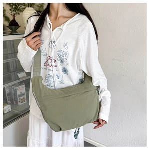 Close-up of green nylon crossbody dumpling bag with wide strap and textured fabric
