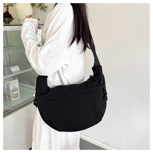 Close-up of a large black crescent crossbody bag in durable nylon worn by a model