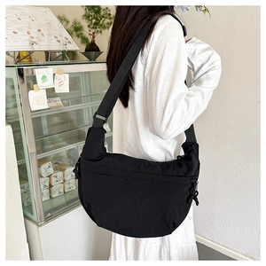 Detail view of black nylon crescent bag featuring a zipper pocket and wide strap
