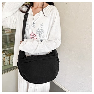 Detail view of a black crescent nylon crossbody bag worn on a casual shoulder strap