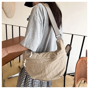 Detail of khaki crescent crossbody bag featuring adjustable strap and white drawstring knot