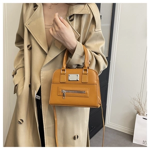 Ginger yellow Boston bag with matte leather texture shown with casual trench coat style