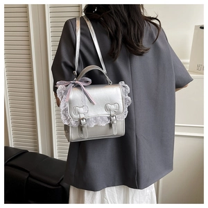 Détail du sac argenté avec dentelle et nœuds, porté à l'épaule pour un style chic