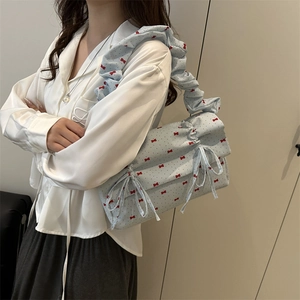 Light blue shoulder bag with red bow prints and a scrunchie strap on model