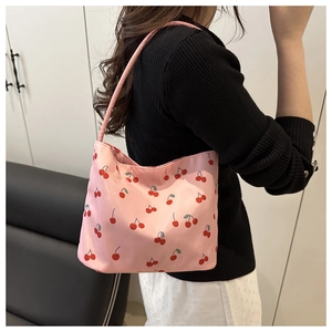 Close-up of small pink shoulder bag featuring cherry patterns and smooth satin texture