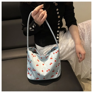 Close-up of light blue nylon tote bag with red cherry prints on a shoulder strap