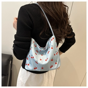Side view of light blue underarm bag featuring cherry patterns and satin-like finish