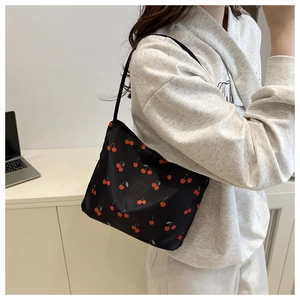 Shoulder bag detail featuring black fabric with red cherry print and zipper closure
