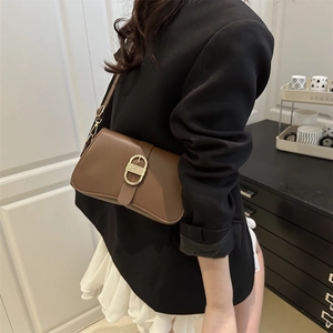 Braune rechteckige Schultertasche aus Leder mit goldener Schnalle am Modell getragen