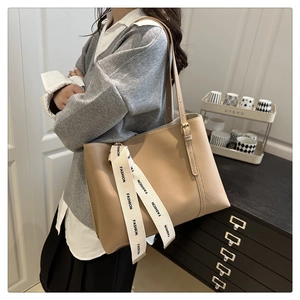 Detail of light brown tote bag with fashion print ribbon on smooth matte leather strap