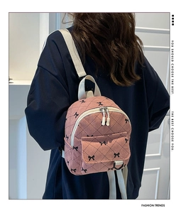 Detail of pink corduroy backpack with black bow pattern and white zipper pockets