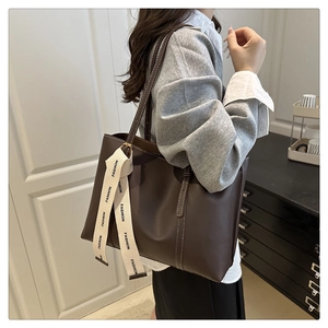 Dettaglio della borsa tote marrone scuro con cuciture bianche e nastro di design