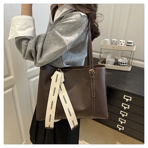Dettaglio borsa tote marrone con cuciture bianche a contrasto e sciarpa di seta decorativa