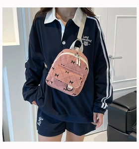 Detail view of pink corduroy mini backpack featuring quilted texture and bow print pattern