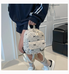 Detail of a mini corduroy backpack featuring black diamond lattice and small bows