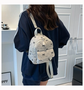 Detailed back view of a beige quilted corduroy backpack with bow patterns and straps