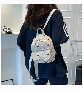 Close-up of mini corduroy backpack with bow patterns on a model's back in a soft interior