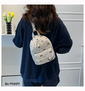 Rear view of model wearing a beige quilted corduroy mini backpack with bow pattern