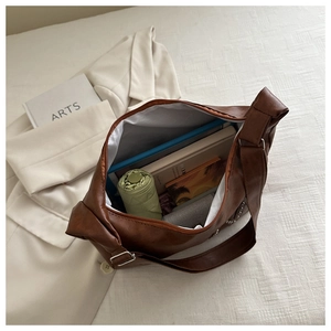 Spacious brown leather tote bag interior showing books, umbrella and metal rivets