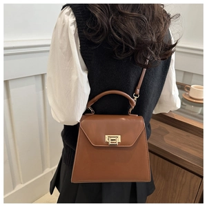 Chic brown leather handbag with gold metal lock buckle shown on model's shoulder