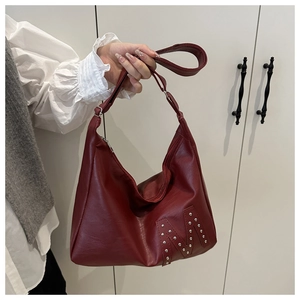 Detail of burgundy PU leather tote bag with silver M-shaped rivet studs on the corner