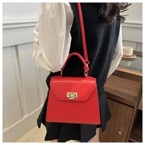 Detailed view of red leather crossbody bag featuring gold buckle and elegant chain strap