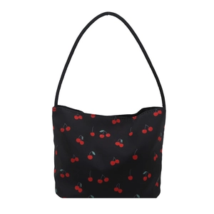 Minimalist black tote bag with red cherry pattern and slim shoulder strap on white backdrop