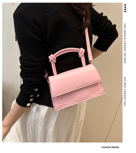 Detailed view of pink candy-colored matte leather handbag with knotted handle and logo