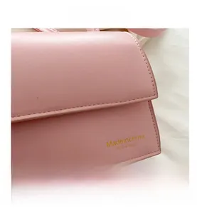 Detail of pink leather handbag showing neat stitching and gold letter printing