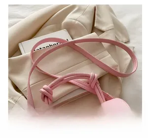 Detail of soft pink leather handbag with knotted handle and adjustable shoulder strap