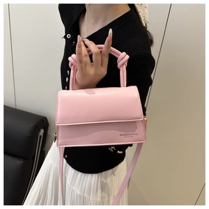 Detail view of pink leather crossbody bag featuring a unique knotted handle design
