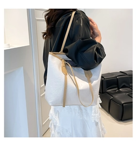 Detail of embossed lettering on white PU leather tote bag with khaki shoulder strap