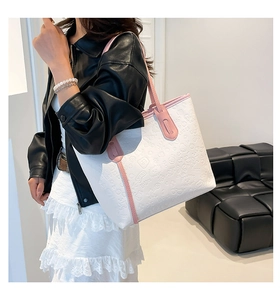 Close-up of embossed patterns and pink strap details on white leather tote bag