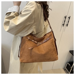 Detail of a brown suede tote bag with crossbody strap and metallic buckle detail