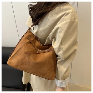 Detail of caramel suede tote bag with leather buckle strap shown on a model