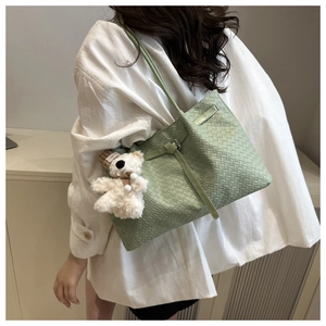 Détail d'un sac cabas tressé vert clair avec un charmant ours en peluche et une bandoulière