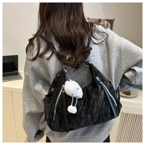 Detail of black wrinkled tote bag with silver zipper and cute plush lamb charm