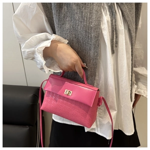 Macro detail of rose pink crossbody bag with houndstooth embossing and gold twist lock