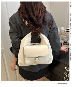 Detail of white hobo bag showing front flap pocket and silver buckle hardware closeup