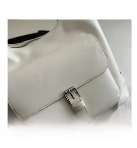Close-up of white PU leather bag detailing front flap pocket and metal buckle buckle